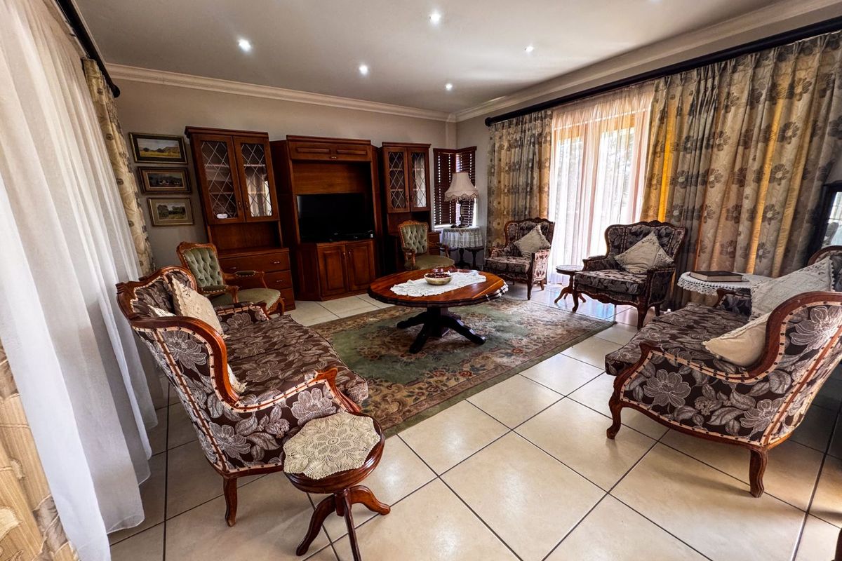Spacious living room featuring large format floor tiles, recessed downlighting, and sliding glass doors providing access to the outdoor area.