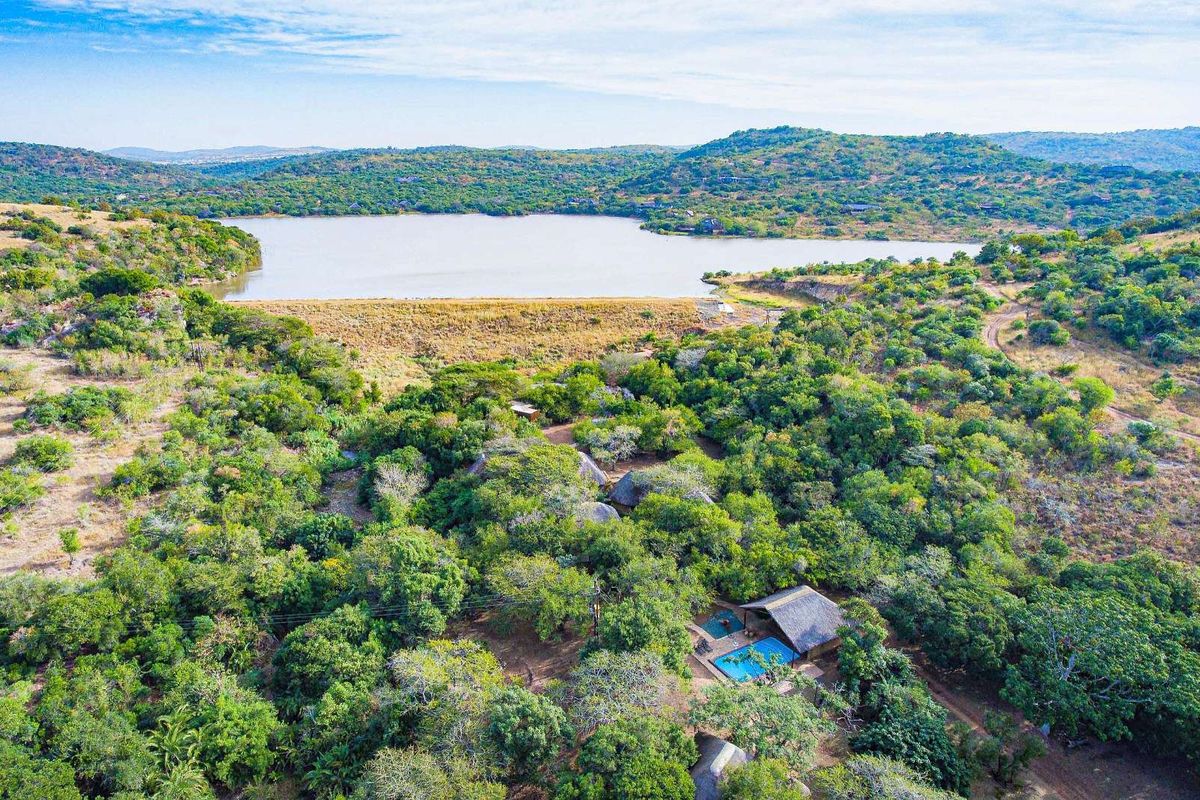 Aerial view of a secluded property nestled in lush natural bushveld, featuring a private swimming pool and scenic views of the nearby lake.