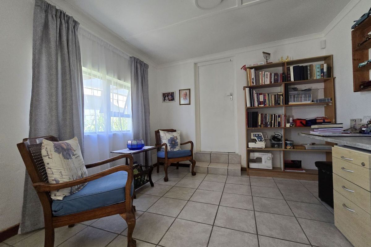 A functional living space featuring tiled flooring, built-in shelving, and a raised doorway leading to an adjacent area.