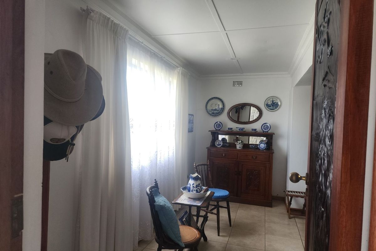 A small, tiled interior room featuring a large window with curtains, suitable for use as a study or sunroom.