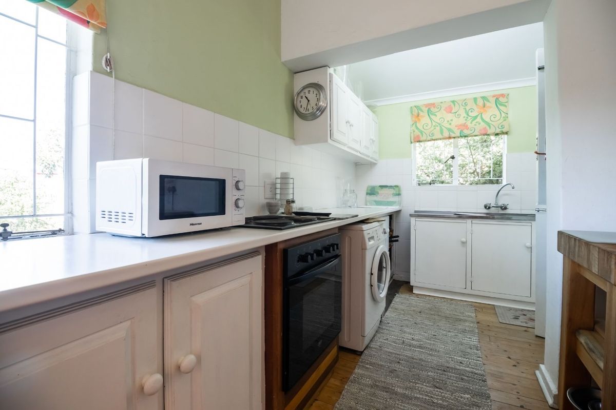 A functional kitchen featuring built-in cabinetry, a stove, oven, and integrated laundry plumbing, offering a practical layout with natural light.