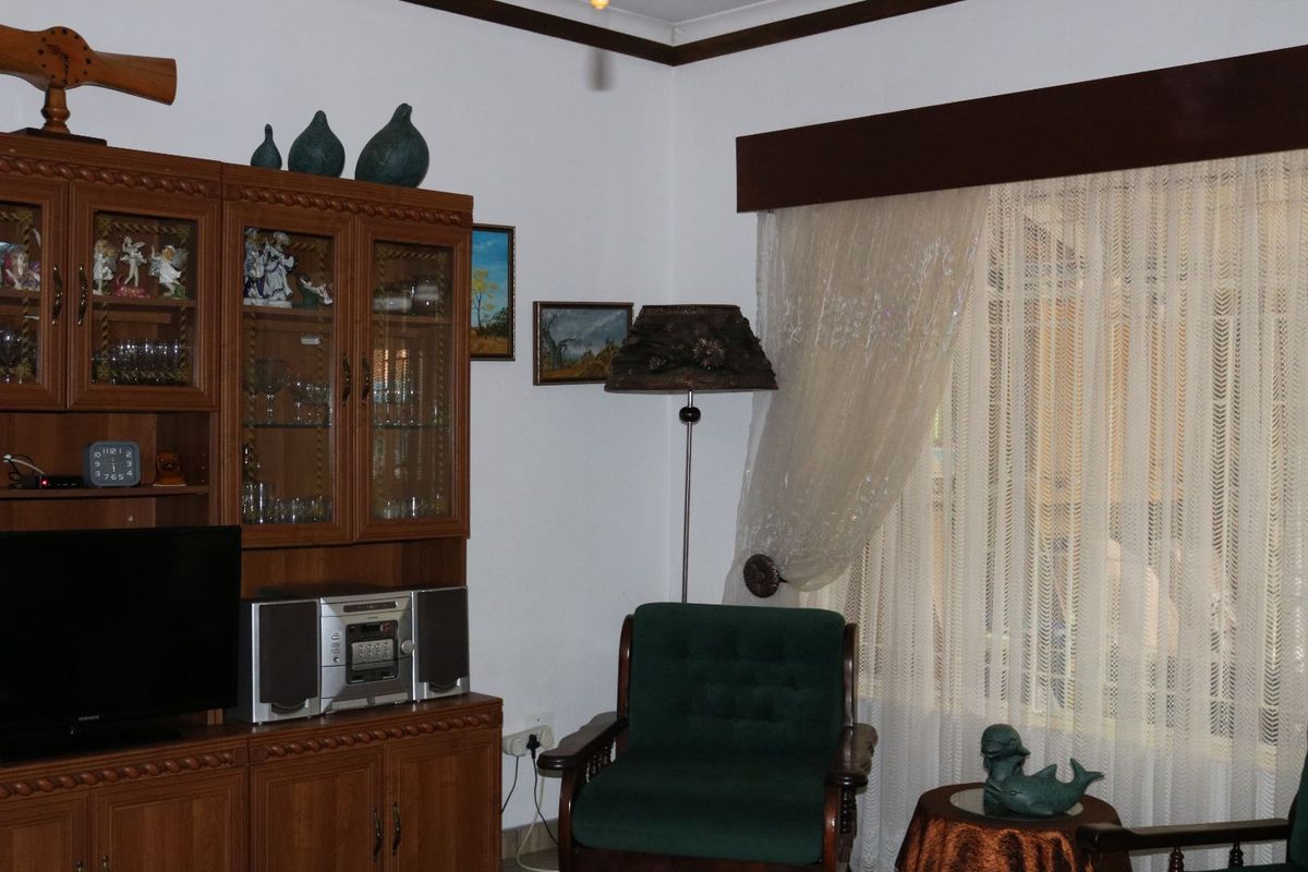 A living room featuring built-in wooden cabinetry and a large window with curtain treatments.