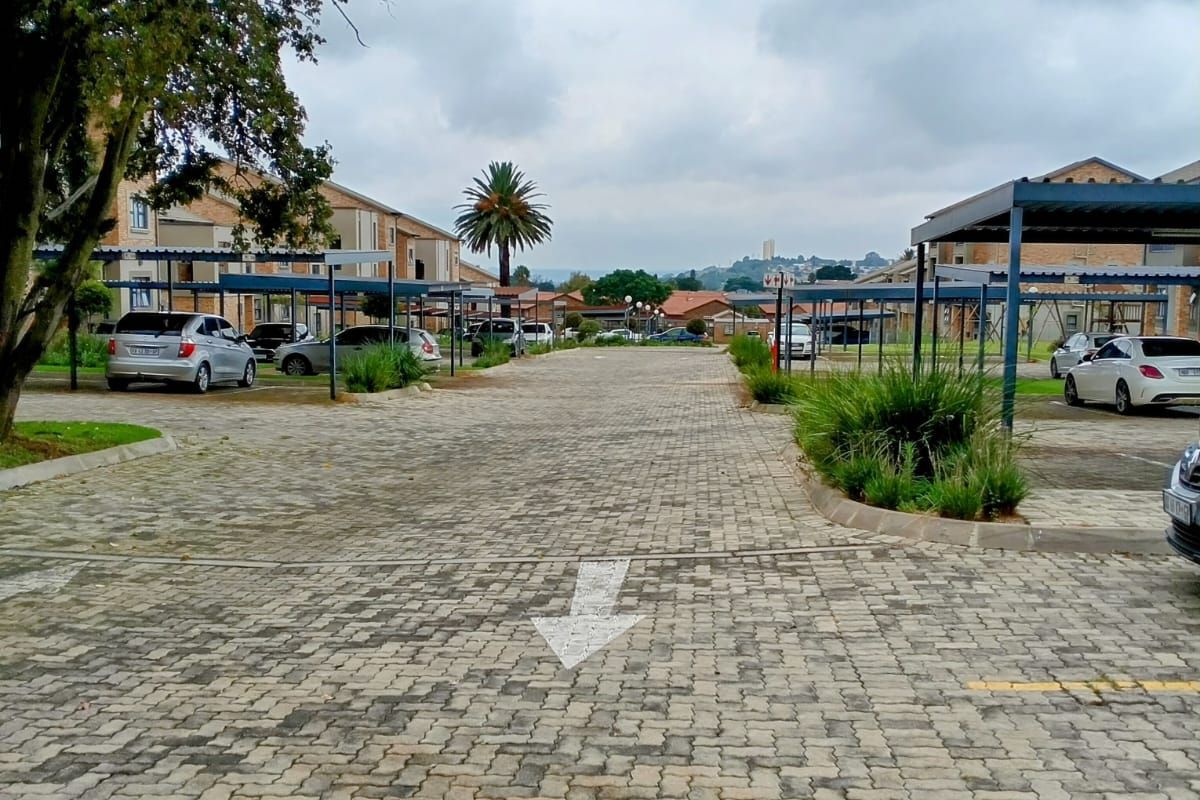 A view of the apartment complex parking area featuring paved driveways and covered parking bays.
