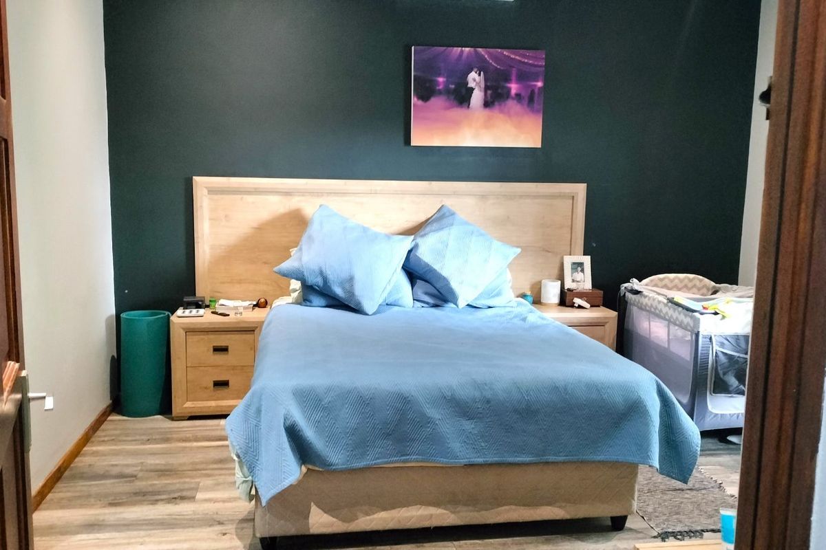 A well-maintained bedroom featuring wood-look flooring and a dark accent wall, providing a cozy and functional sleeping space.