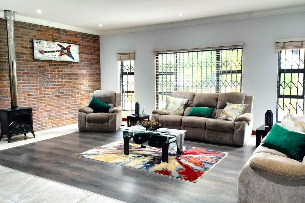 Spacious living room featuring a prominent exposed brick feature wall, a freestanding wood-burning fireplace, and large windows with security bars.