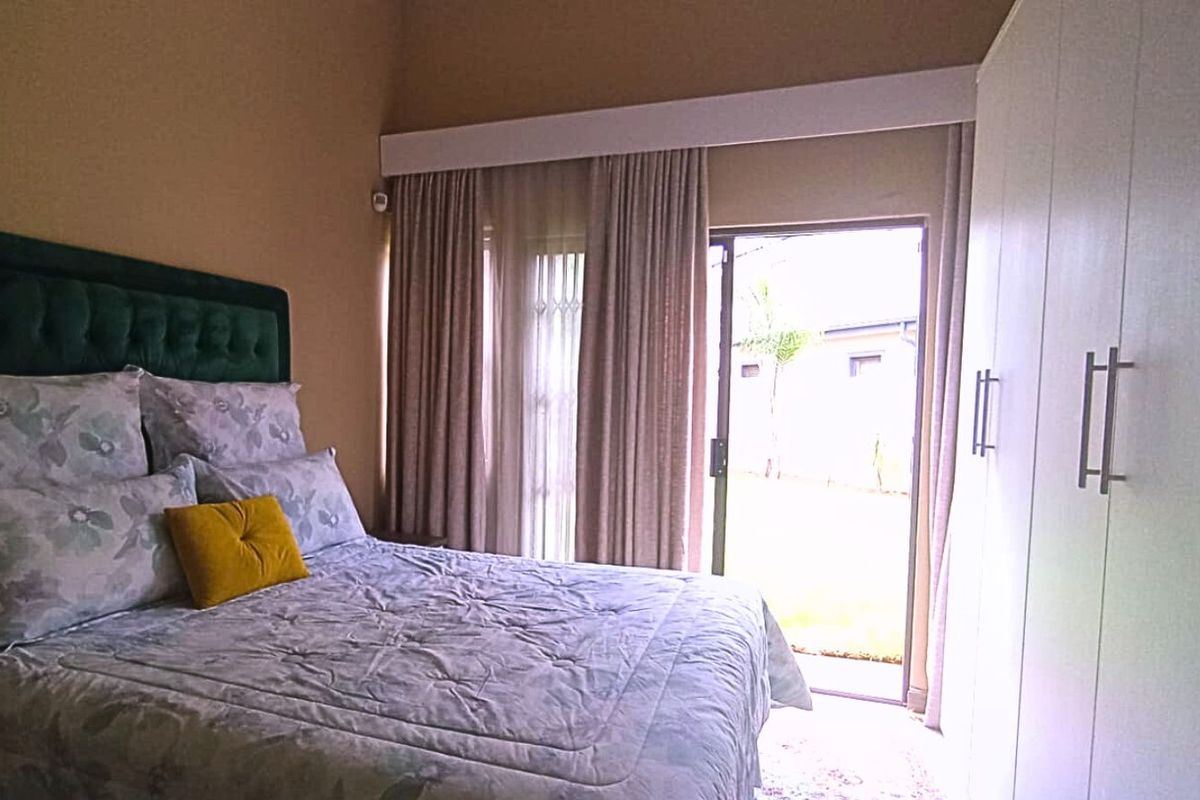 A well-lit bedroom featuring built-in wardrobes, high ceilings, and a sliding glass door providing direct access to the outdoor area.
