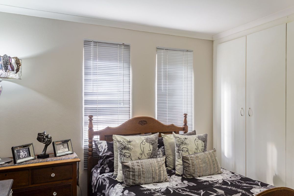 A bedroom featuring built-in wardrobes and dual windows with fitted venetian blinds.