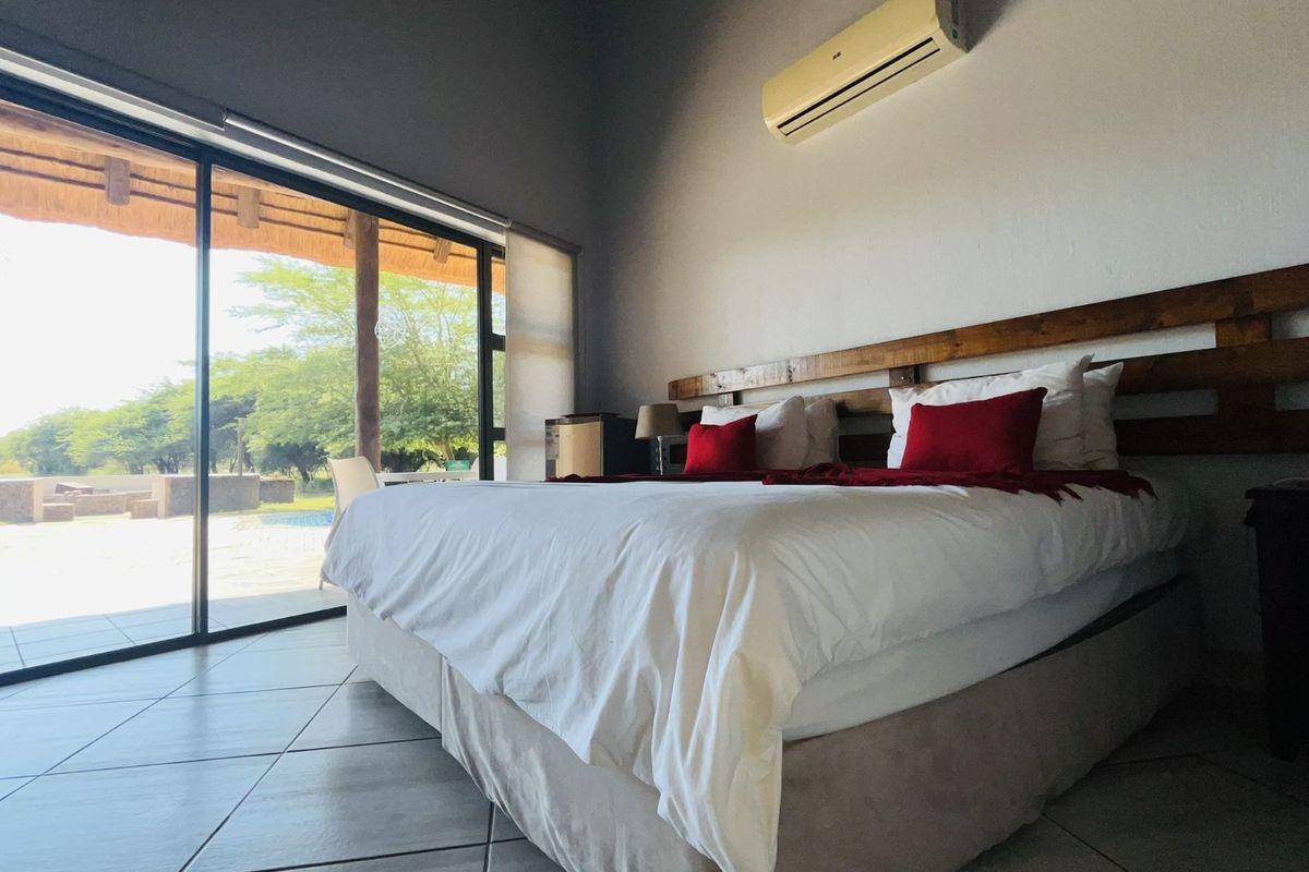 Spacious bedroom featuring tiled flooring, a built-in wooden headboard, and large sliding glass doors providing direct access to an outdoor patio area.