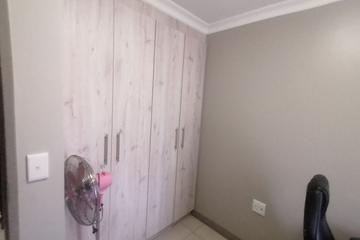 A bedroom featuring built-in light wood-grain cabinetry with modern handles and neutral wall finishes.