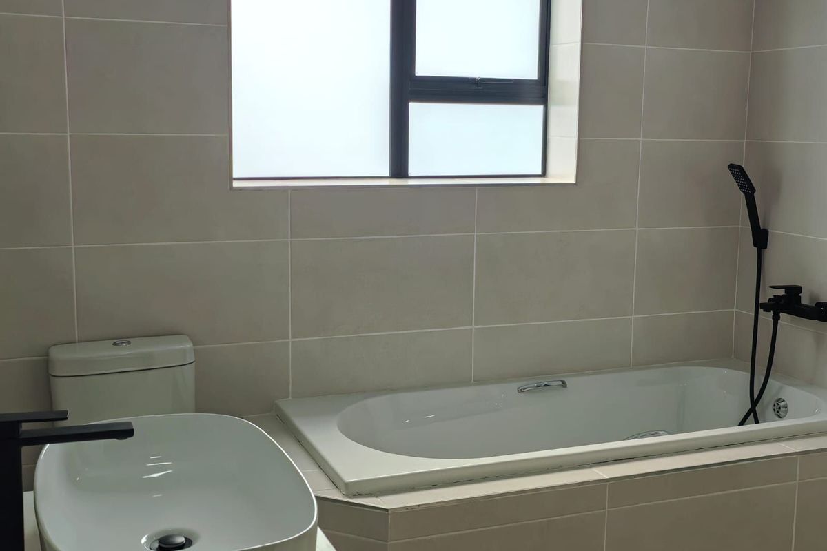 Modern bathroom featuring a built-in bathtub, contemporary vessel sink, matte black fixtures, and neutral wall tiling.