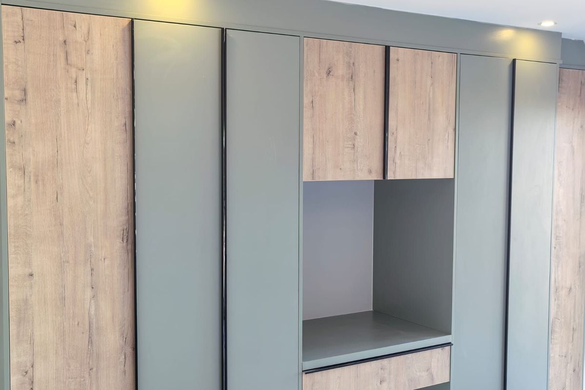 Modern built-in cabinetry featuring a contemporary mix of wood-grain and matte sage green finishes with integrated recessed lighting.