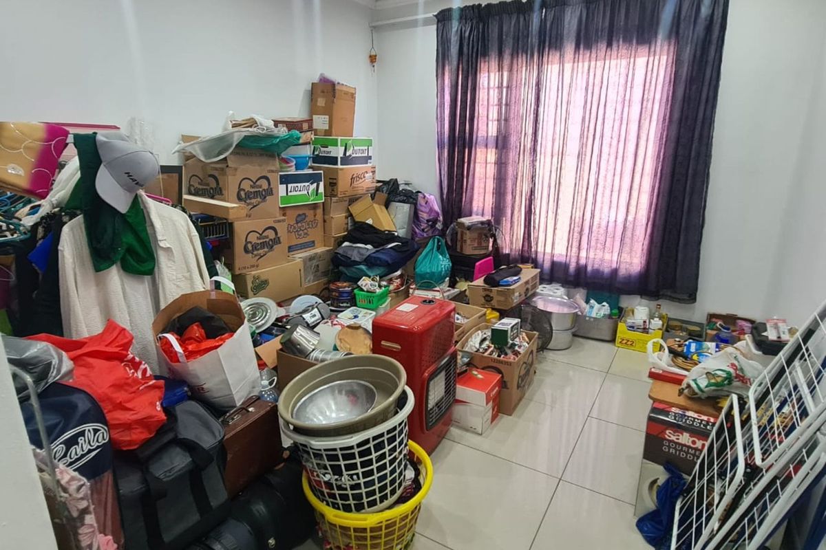 A multi-purpose room featuring tiled flooring and a large window with dark curtains, currently utilized for storage.