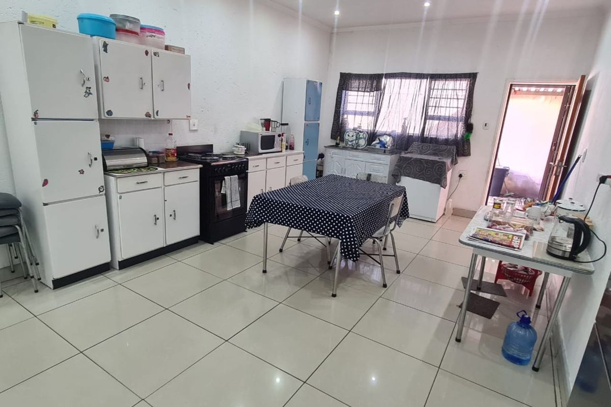 A functional kitchen featuring white cabinetry, tiled flooring, and recessed ceiling lighting, offering a practical space for meal preparation and casual dining.