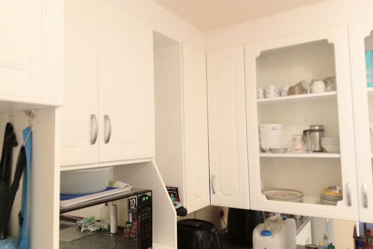 A kitchen area featuring white cabinetry with integrated shelving and a dedicated microwave nook.