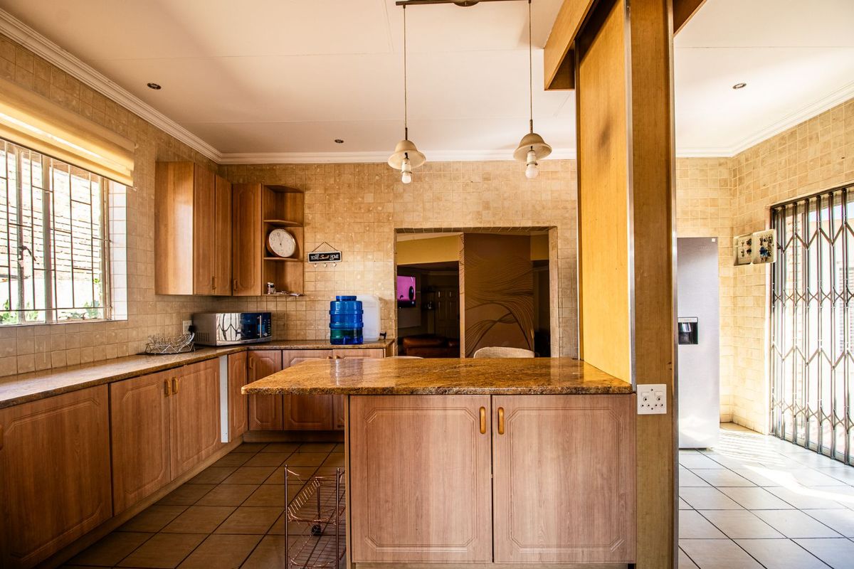 A functional kitchen featuring wood-look cabinetry, granite-style countertops, tiled flooring, and a breakfast bar, offering a practical layout for daily meal preparation.