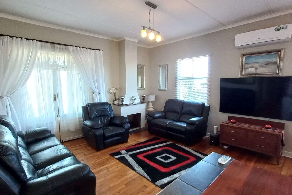 A comfortable living room featuring hardwood flooring, a fireplace, and a wall-mounted air conditioning unit, with direct access to the outdoors via french doors.