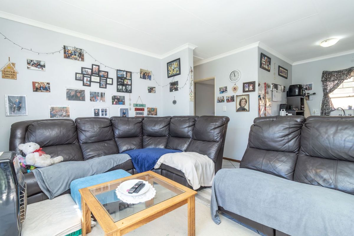 A comfortable living room area featuring tiled flooring, neutral wall finishes, and coved ceiling detailing, providing a functional space for relaxation.
