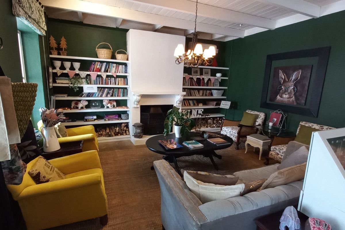 Cozy retail lounge area featuring a central fireplace, built-in shelving units, and exposed white timber ceiling beams.