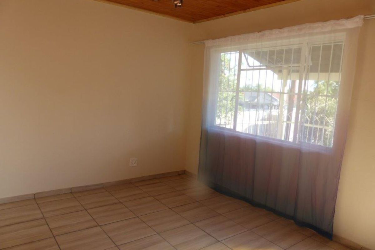 A bright, empty living room featuring tiled flooring and a timber-clad ceiling, offering a versatile space ready for personalization.