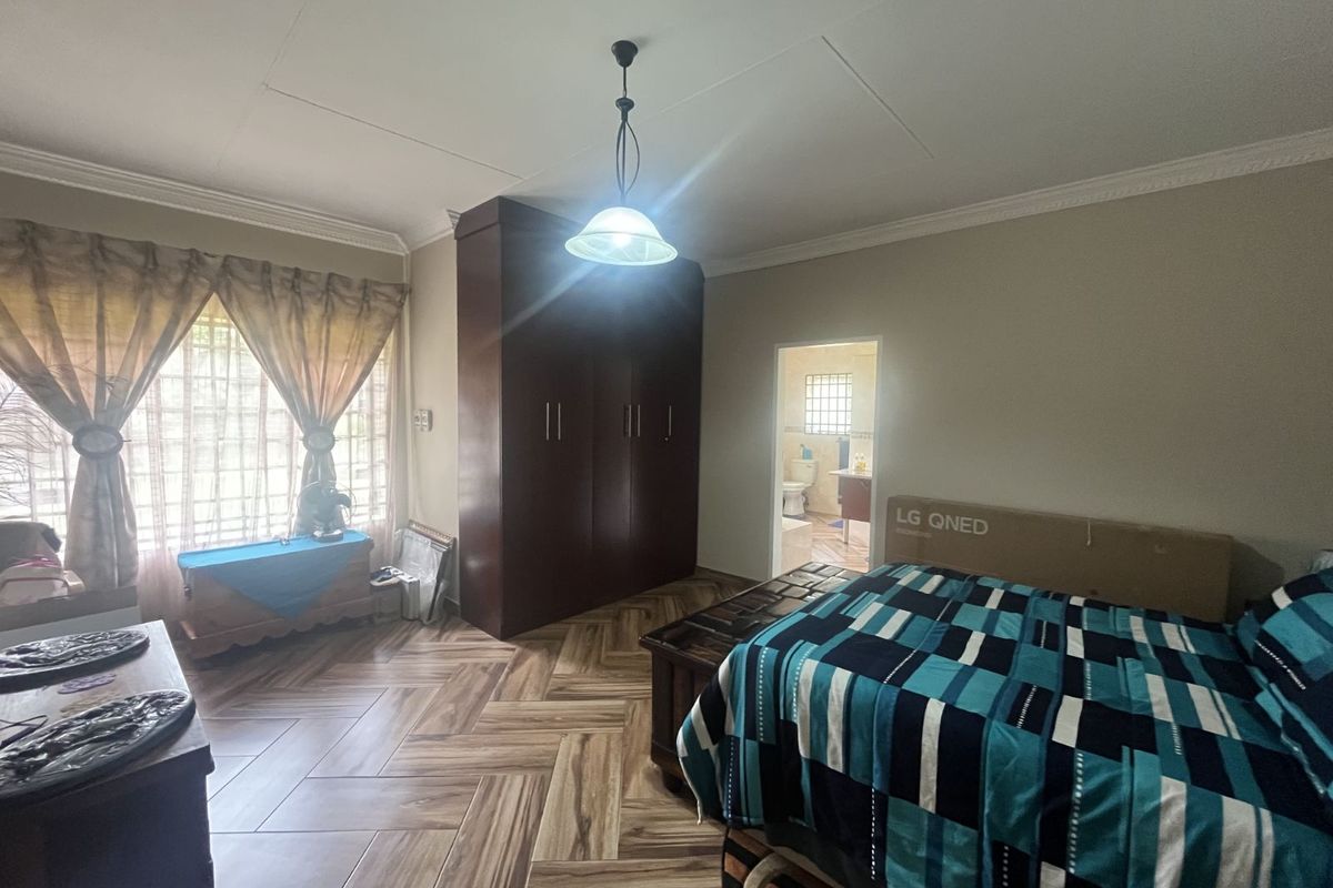 A spacious bedroom featuring wood-look tiled flooring, built-in cabinetry, and an en-suite bathroom access.