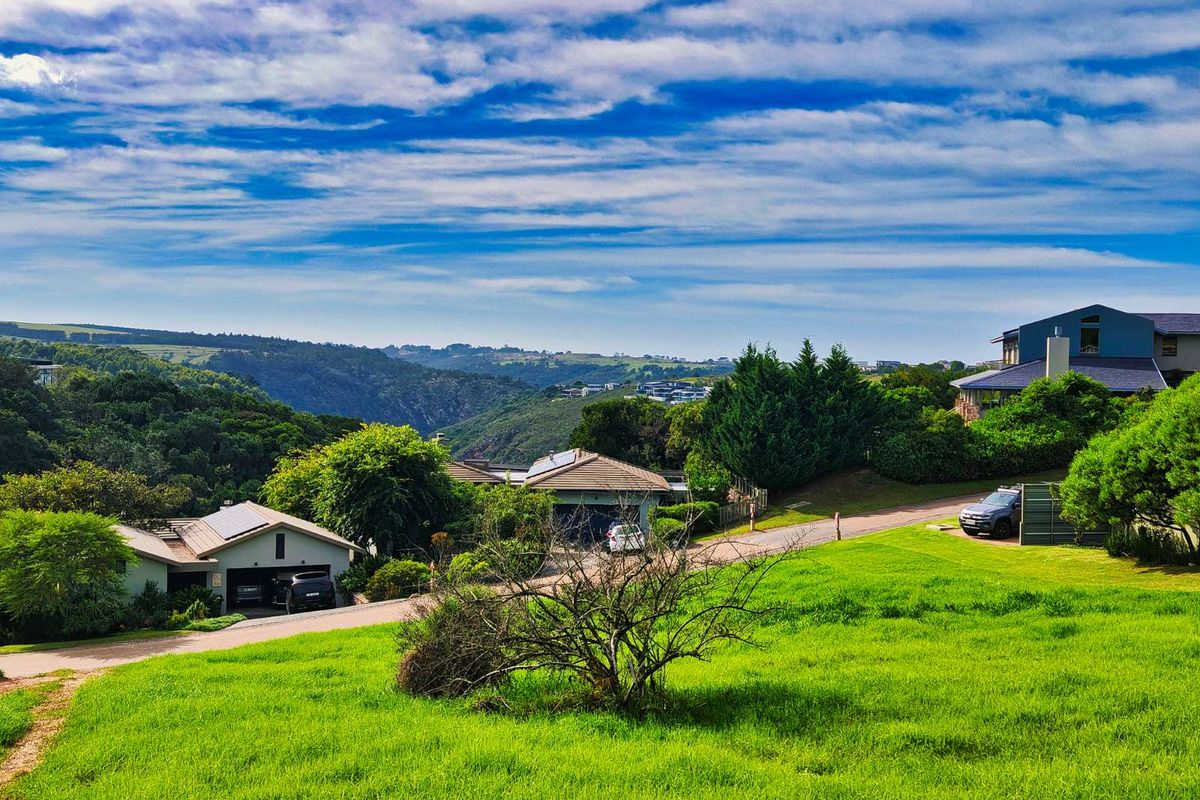 A scenic elevated view overlooking a residential neighborhood with lush green hills and valley landscape in the background.
