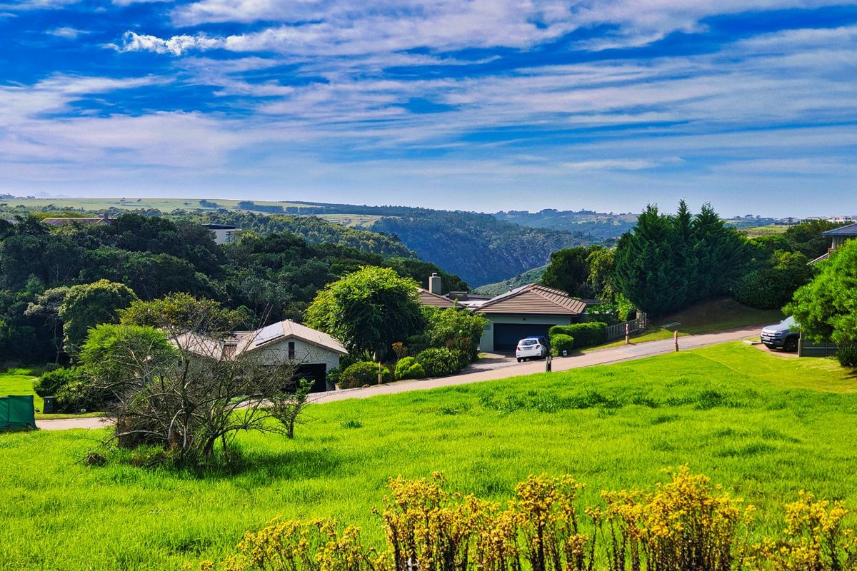 A scenic view overlooking a lush green landscape with established residential properties and rolling hills in the background.