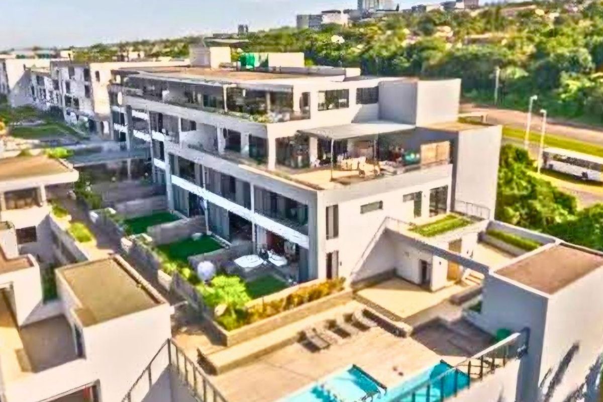 Aerial view of a modern apartment complex featuring multi-level terraces, private garden spaces, and a communal swimming pool area.
