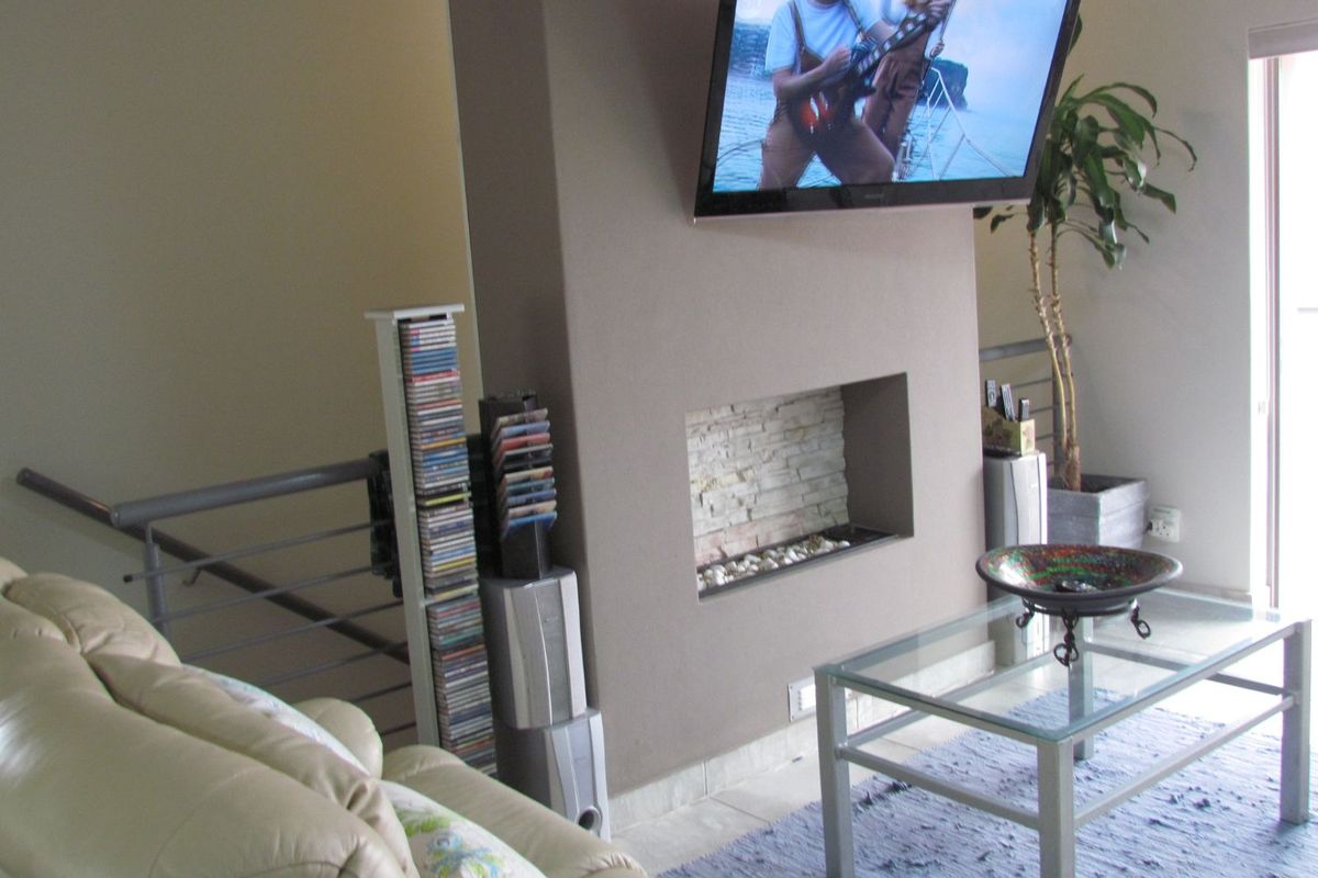 Living room featuring a central fireplace with stone cladding detail and a wall-mounted television.
