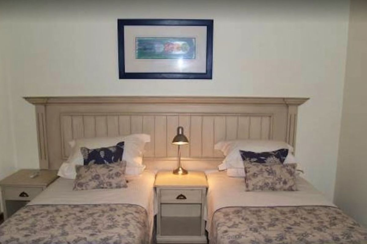 A bedroom featuring a built-in wooden headboard with integrated bedside tables, providing a functional and classic sleeping arrangement.