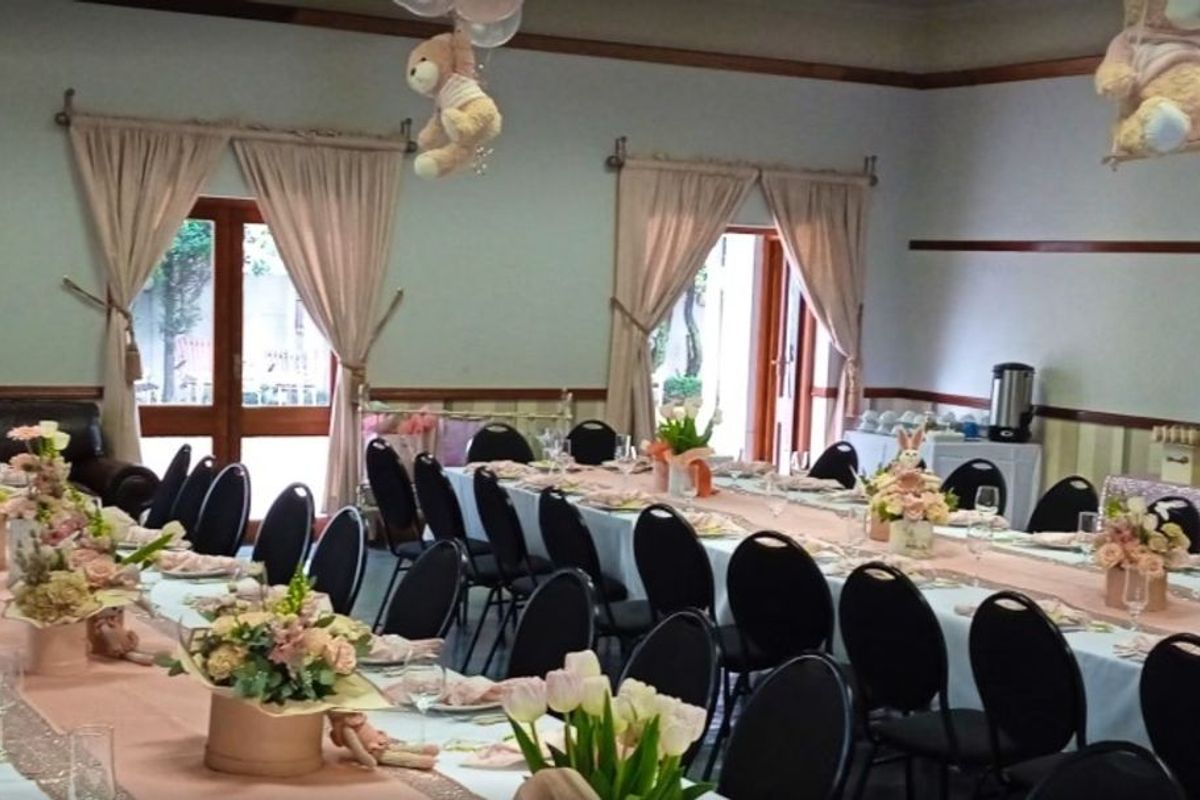 A spacious commercial function room featuring wooden door frames, dado rails, and large windows providing natural light, suitable for events and gatherings.