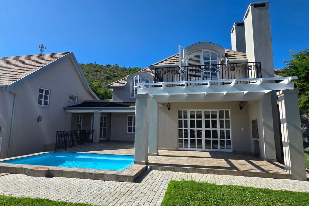 Rear view of the property featuring a swimming pool, paved patio area, pergola, and a balcony with wrought iron railings.