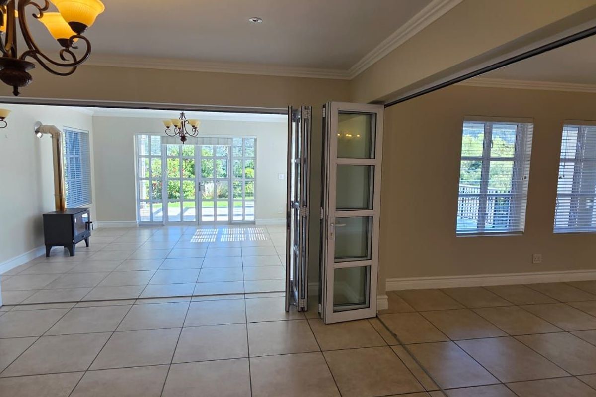 Spacious living area featuring large white aluminum folding doors that open to an adjacent sunroom, tiled flooring, and a built-in wood-burning fireplace.