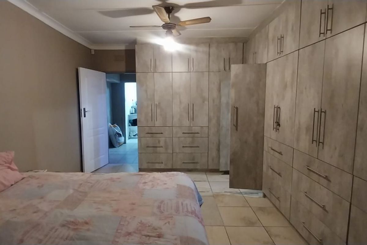 Spacious bedroom featuring extensive built-in cabinetry with a modern textured finish, ceiling fan, and tiled flooring.