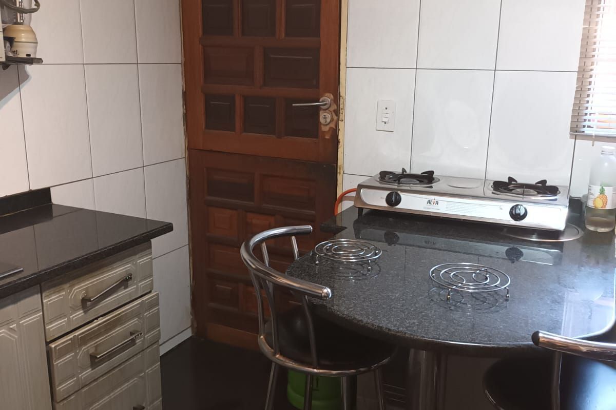 A compact kitchen featuring granite countertops, built-in cabinetry, and a gas hob, providing a functional workspace with direct access to an exterior door.
