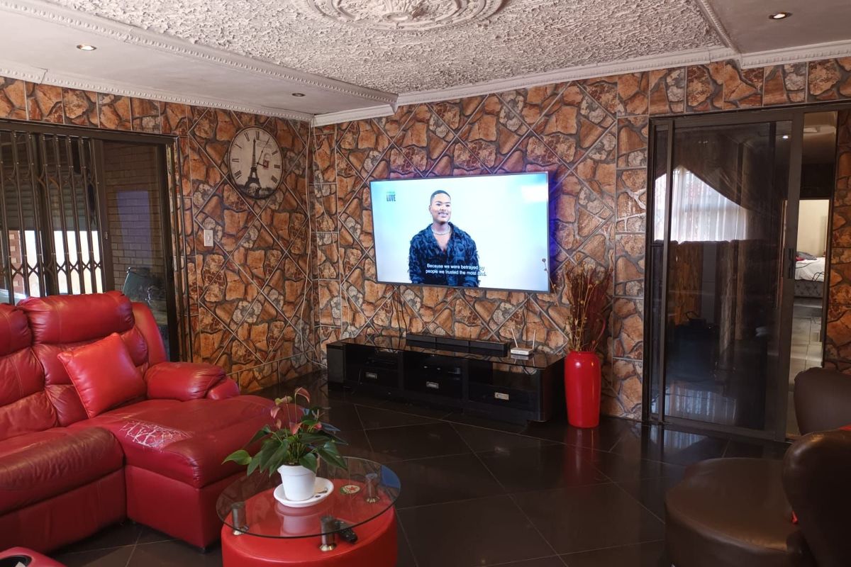 Living room featuring dark floor tiles, a decorative ceiling rose, and stone-effect wall cladding with integrated sliding door access.