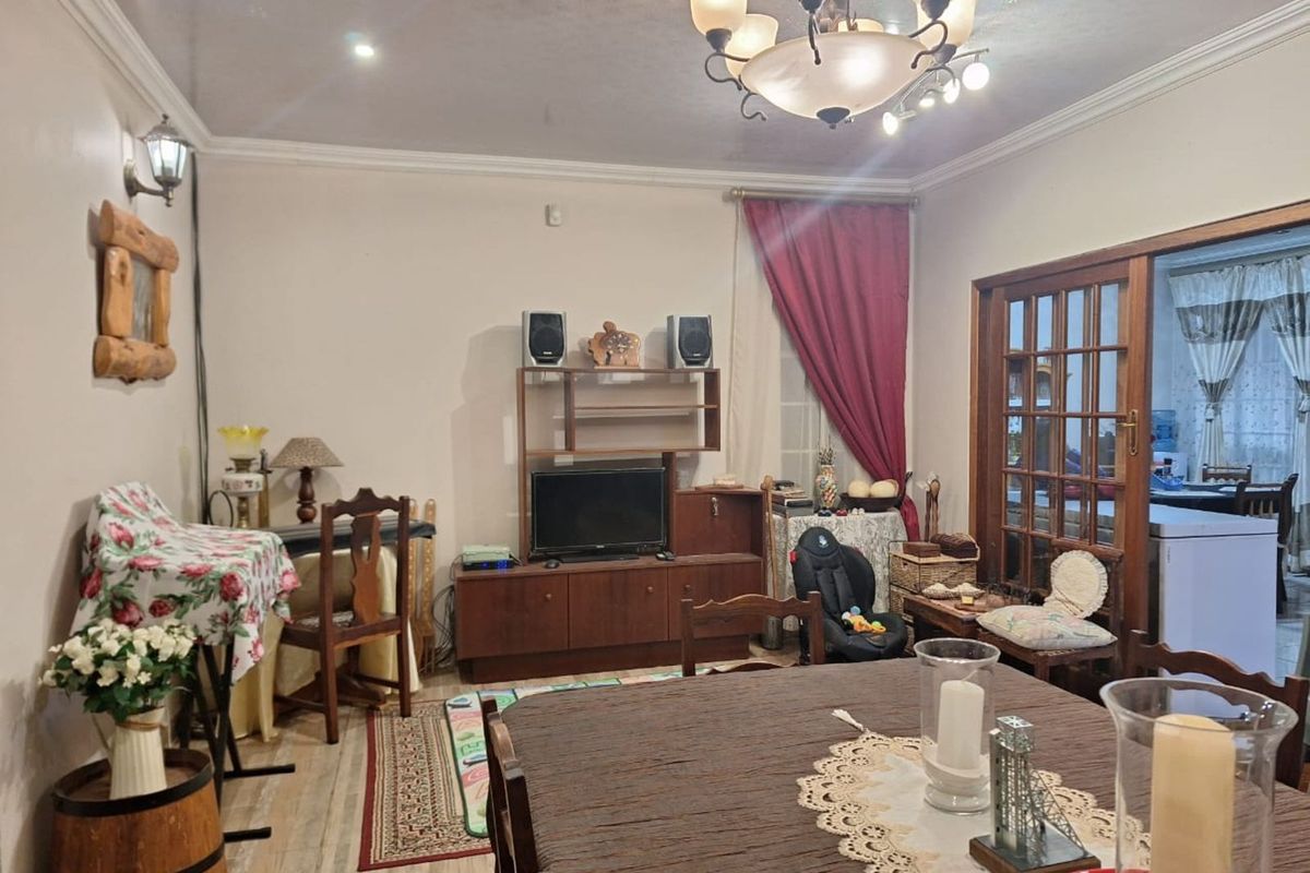A living and dining area featuring tiled flooring, crown molding, and a wooden sliding door leading to an adjacent room.