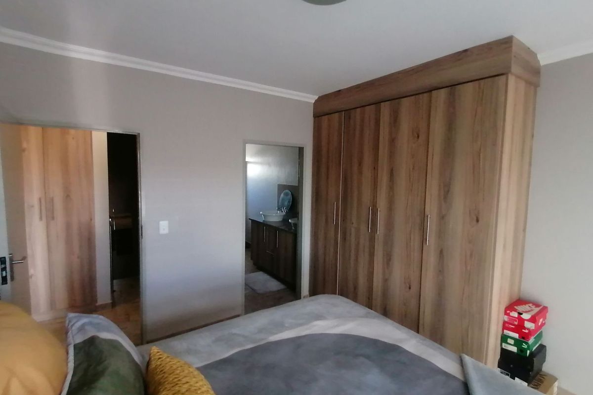 A well-maintained bedroom featuring built-in wooden cabinetry and direct access to an en-suite bathroom.