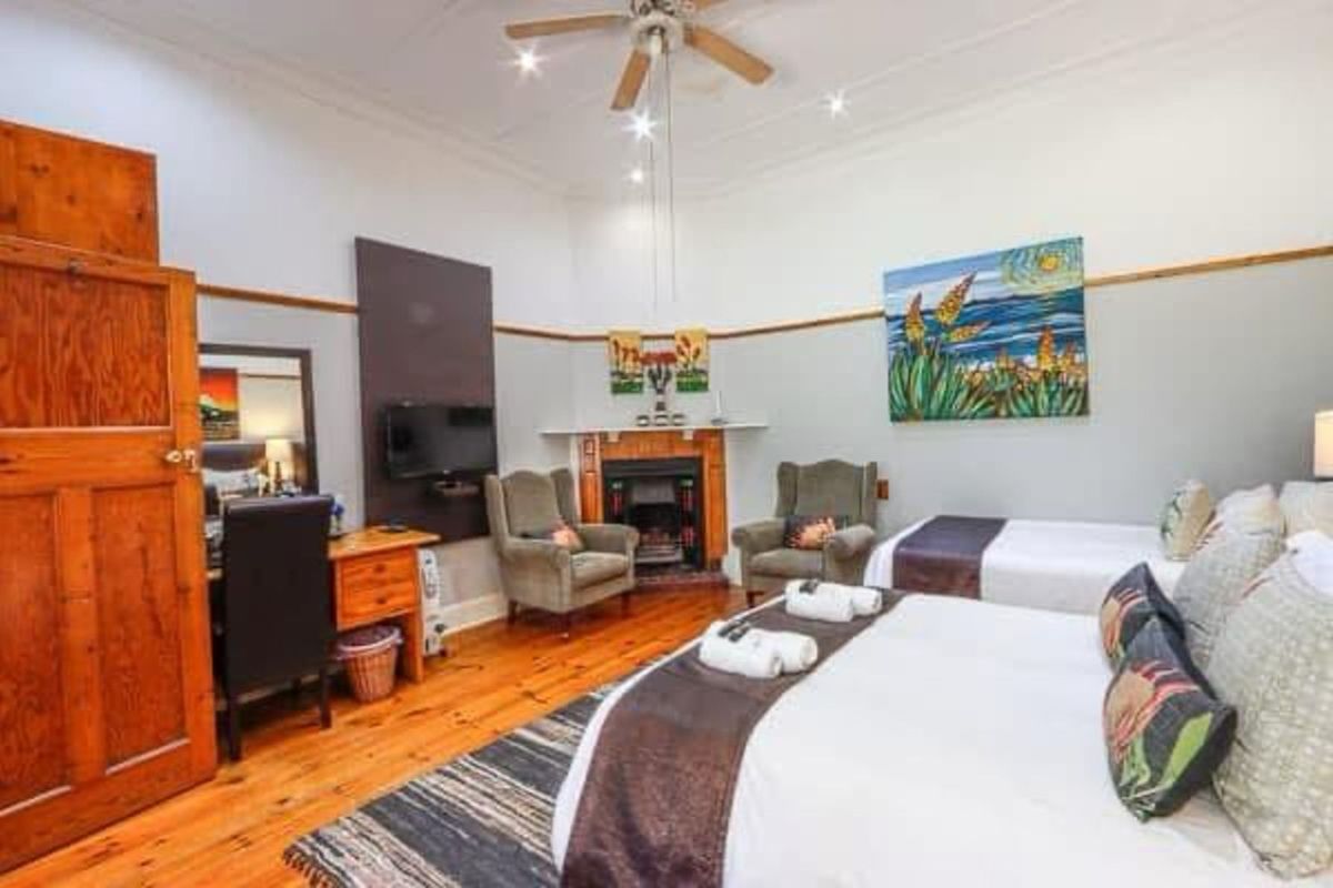 Spacious bedroom featuring high ceilings, original timber flooring, a built-in fireplace, and a ceiling fan.