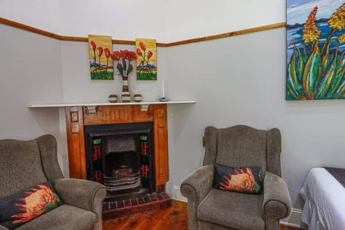 A cozy living area featuring a traditional wooden fireplace mantel with decorative tile inserts and polished timber flooring.