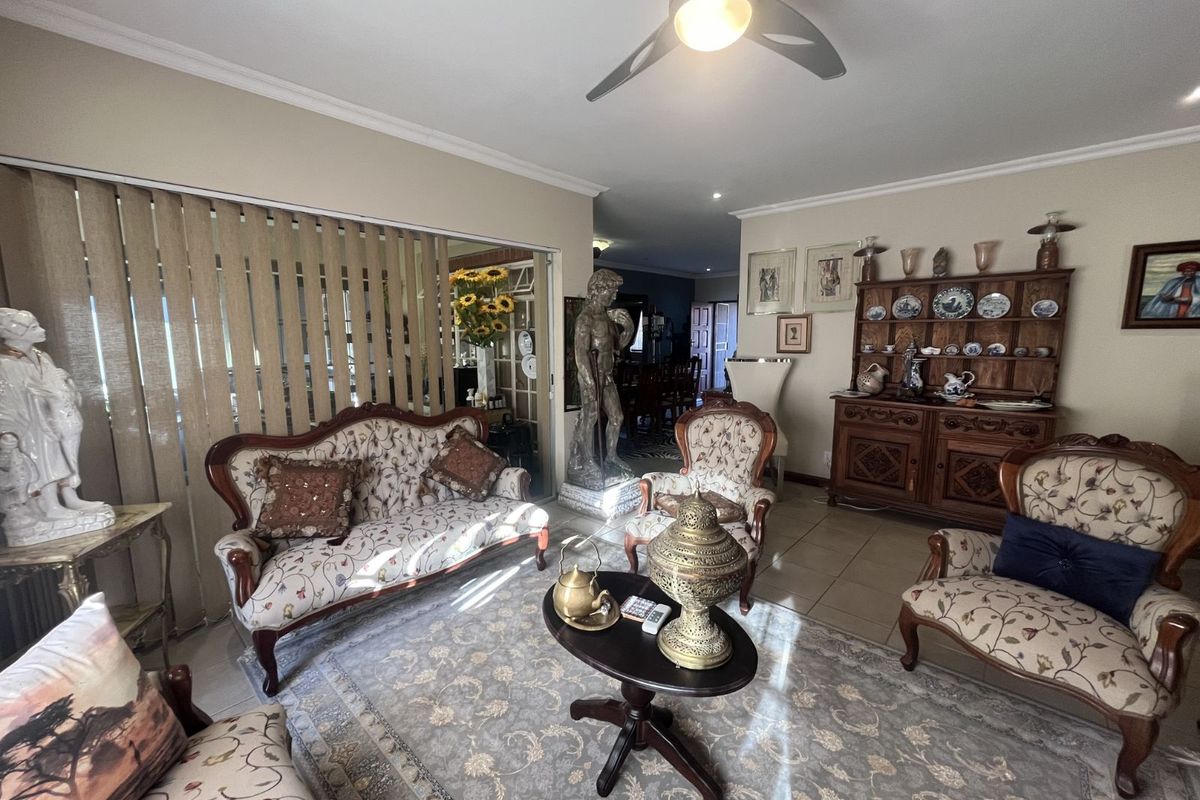 A spacious living room featuring tiled flooring, a ceiling fan, and large sliding glass doors leading to an adjacent area.