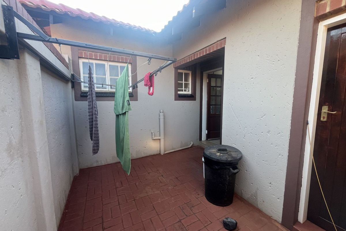 A functional exterior courtyard area featuring brick paving, a wall-mounted drying rack, and access to the main dwelling.