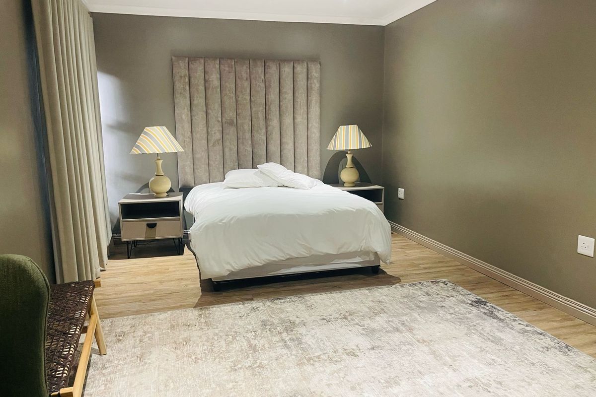 A well-maintained bedroom featuring neutral wall tones, wood-look flooring, and recessed ceiling lighting.