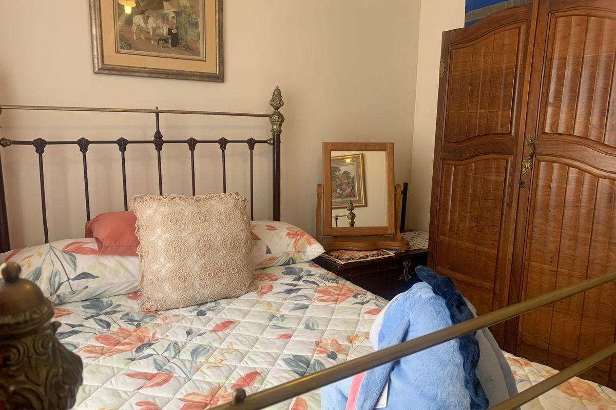 A cozy bedroom featuring a classic metal bed frame and a traditional wooden wardrobe, offering a warm and inviting atmosphere.