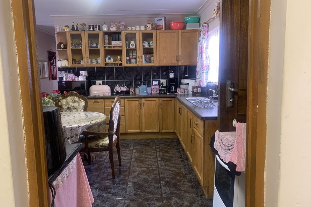 A functional kitchen featuring wooden cabinetry, dark tiled flooring, and a tiled backsplash, offering a traditional layout with ample storage space.