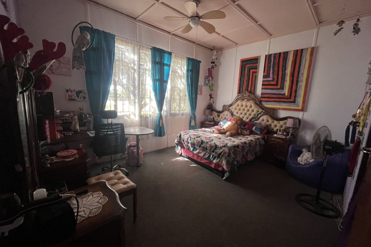 A spacious bedroom featuring a ceiling fan, large windows with natural light, and traditional wall paneling details.