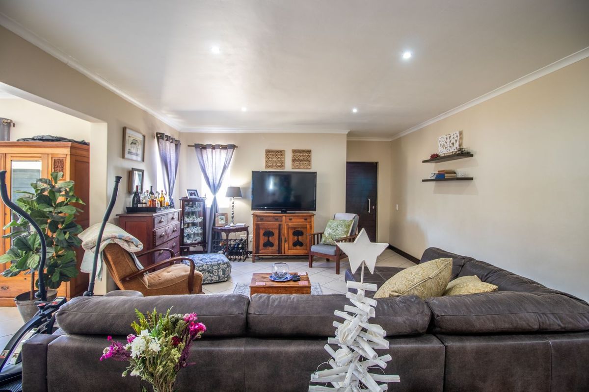 A spacious living room featuring tiled flooring, recessed ceiling lighting, and neutral wall finishes, providing a comfortable and functional central living area.