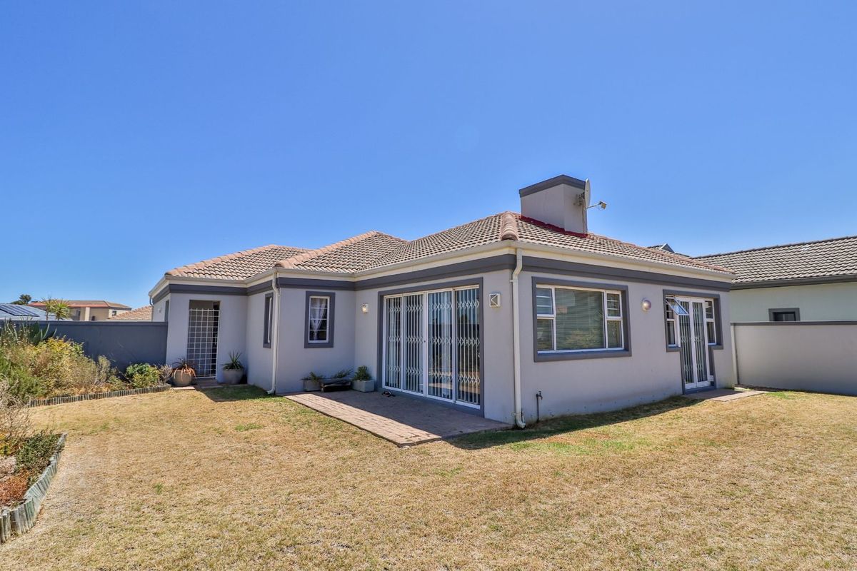 Rear view of the house featuring a paved patio area, tiled roof, and a well-maintained garden space.