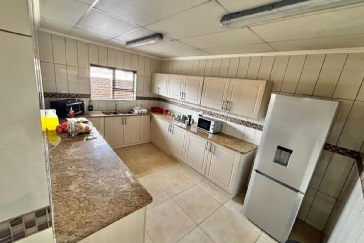 Functional kitchen featuring granite countertops, ample cabinetry, tiled walls, and tiled flooring in an industrial-style setting.