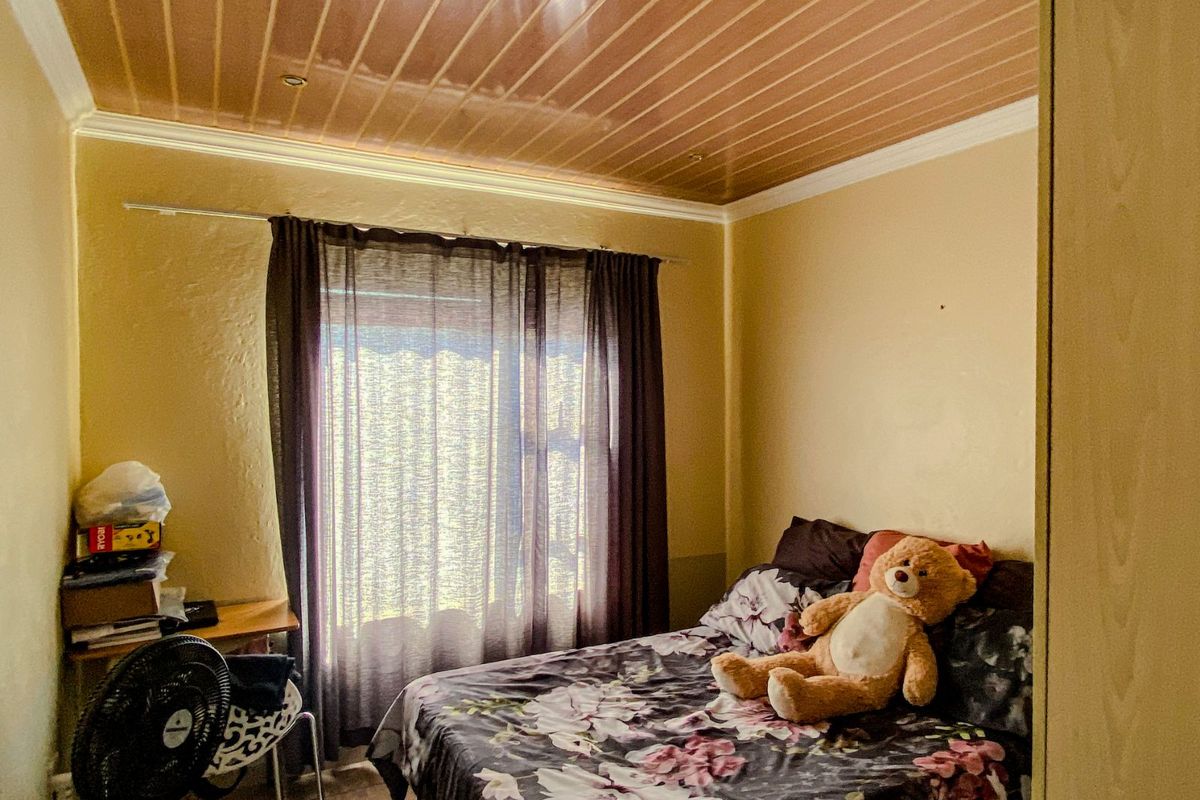 A bedroom featuring a glossy wood-look ceiling, tiled flooring, and a window with curtain tracks.