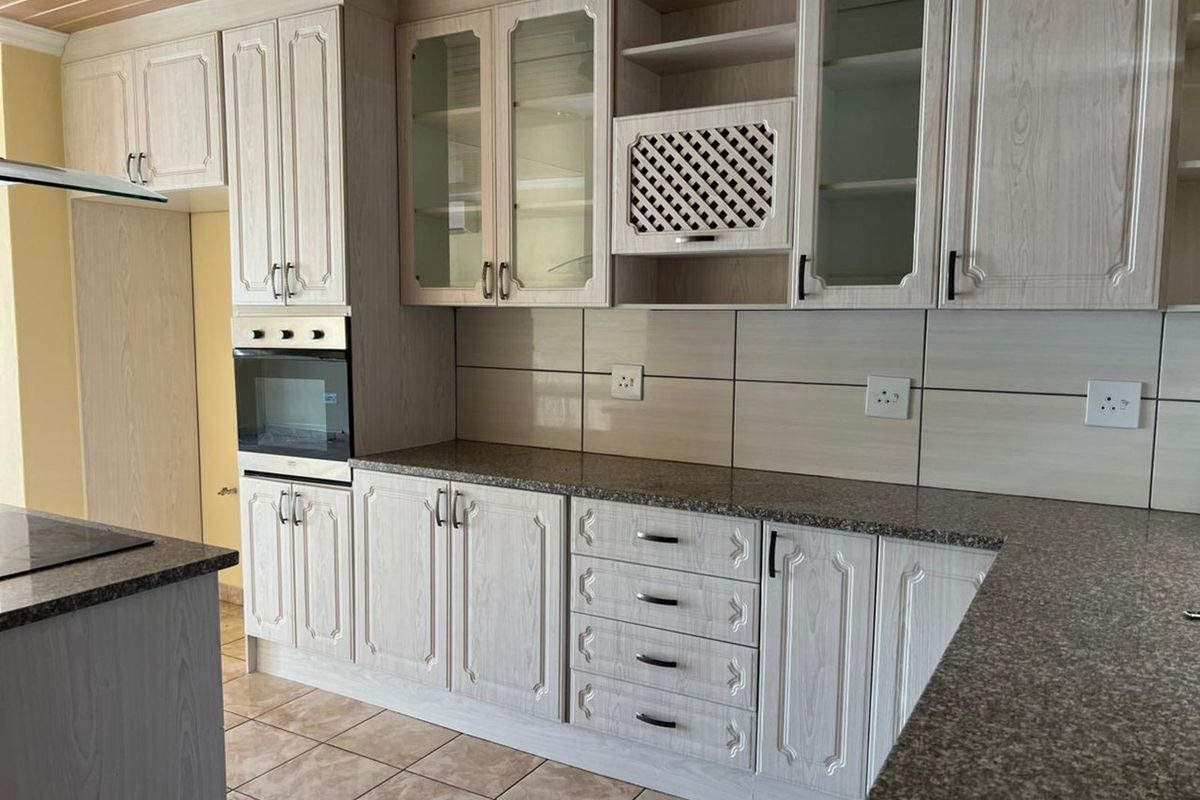 A functional kitchen featuring light wood-grain cabinetry, granite countertops, built-in oven, and tiled flooring.